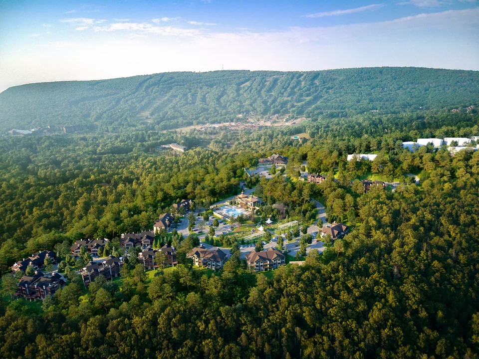 Aerial of resort lodges among forest below ski slopes in Tannersville, Pennsylvania, at sunset