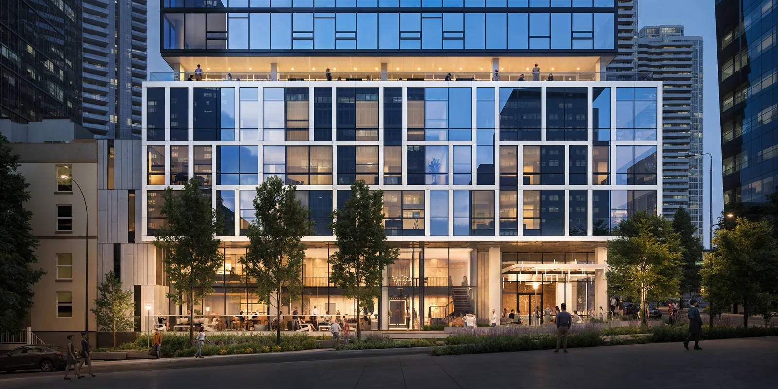 Glass tower base with lit restaurant and street trees at night in downtown Seattle