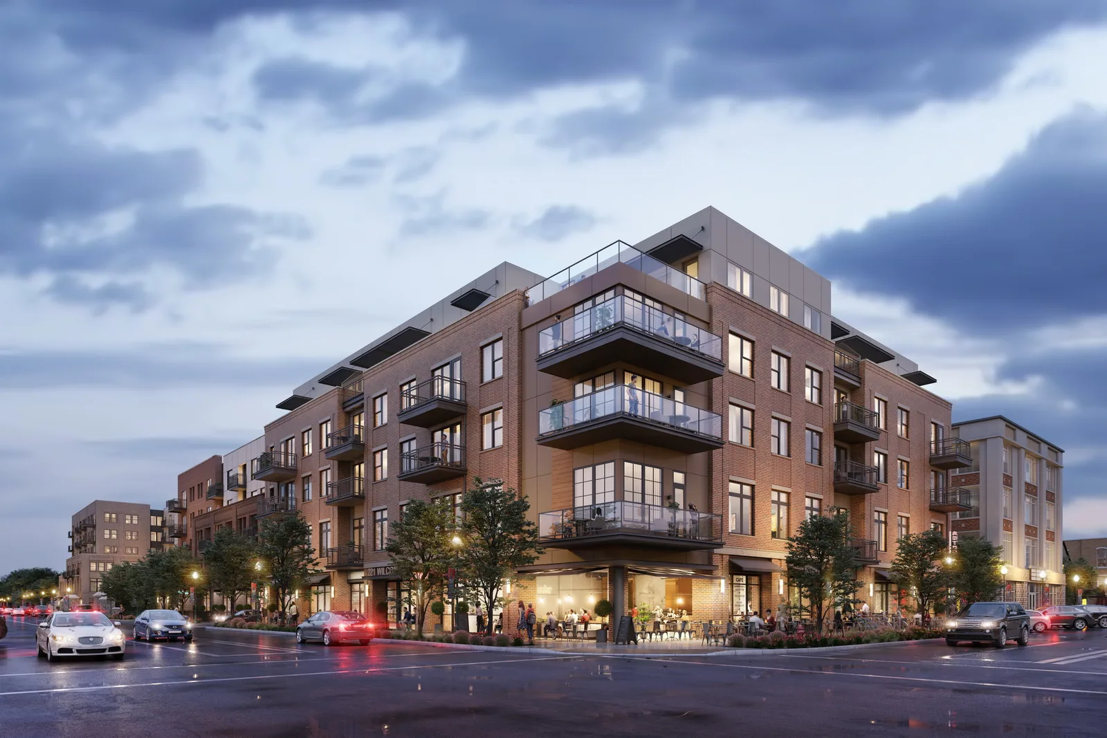 Brick Riverwalk Castle Rock building at 221 Wilcox Street with glass balconies and lit shops at dusk