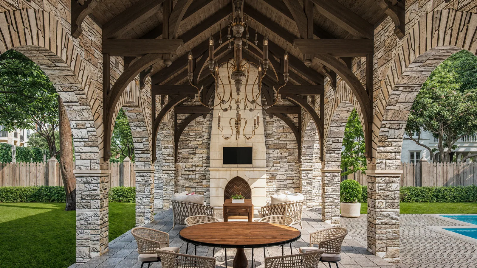 Vaulted stone loggia with fireplace, chandelier and round table at 842 Friar Tuck, Houston