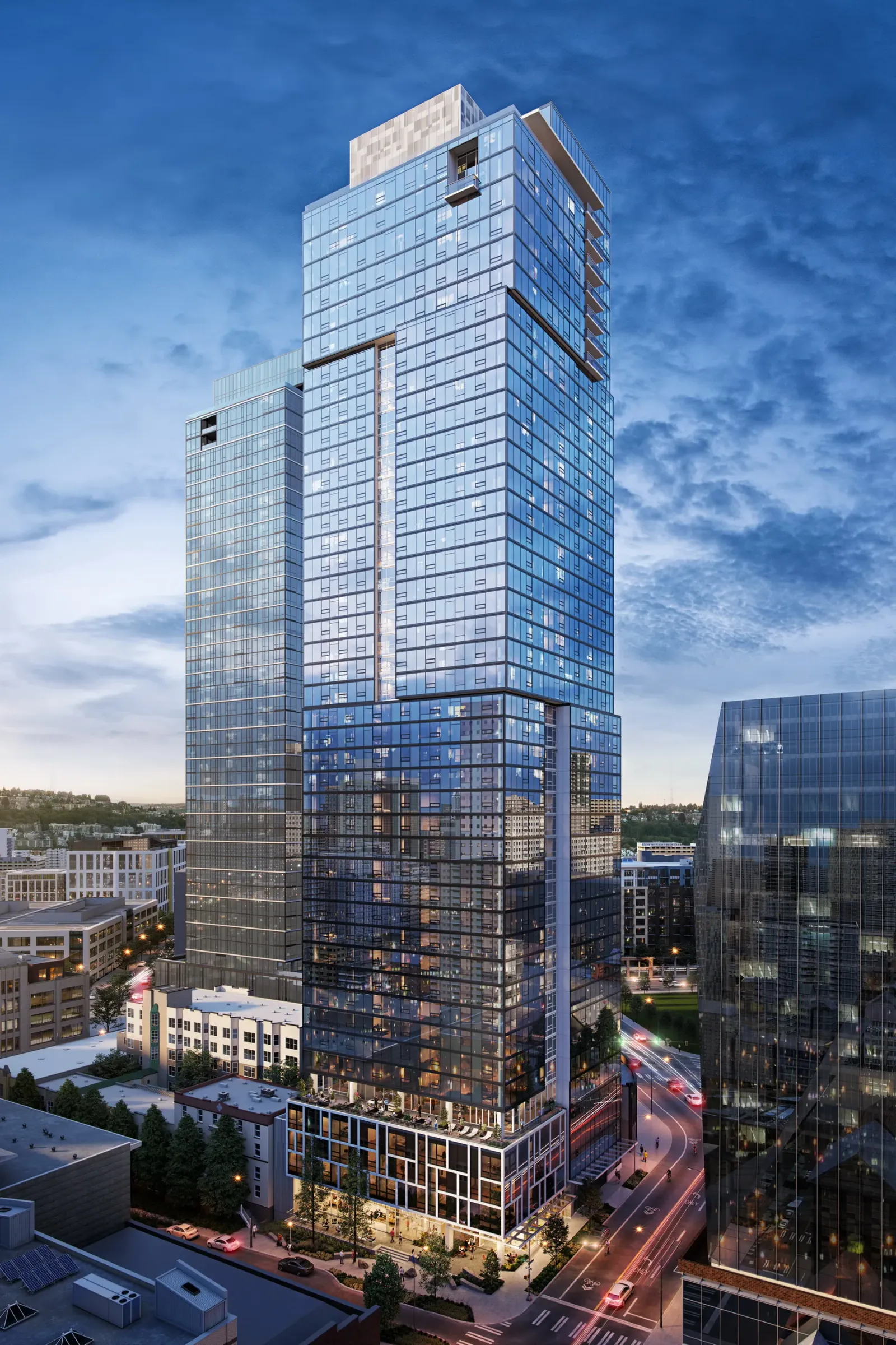 Blue glass Ayer tower in Seattle at dusk rising above neighboring buildings