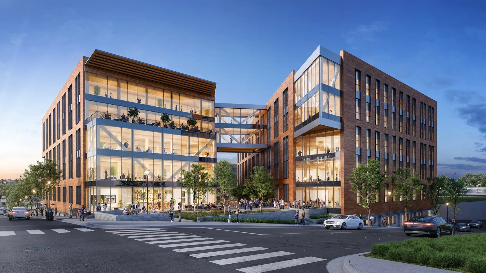Brick and glass office buildings with terraces and a sky bridge at Platform in Raleigh at dusk