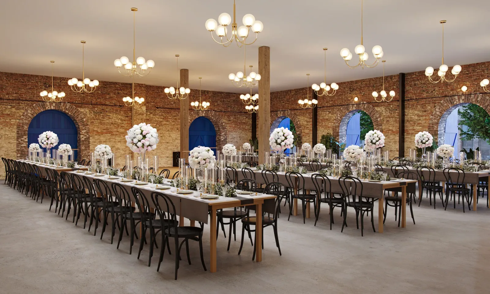 Event hall with long banquet tables, white flowers and chandeliers under brick walls at Common House New Orleans