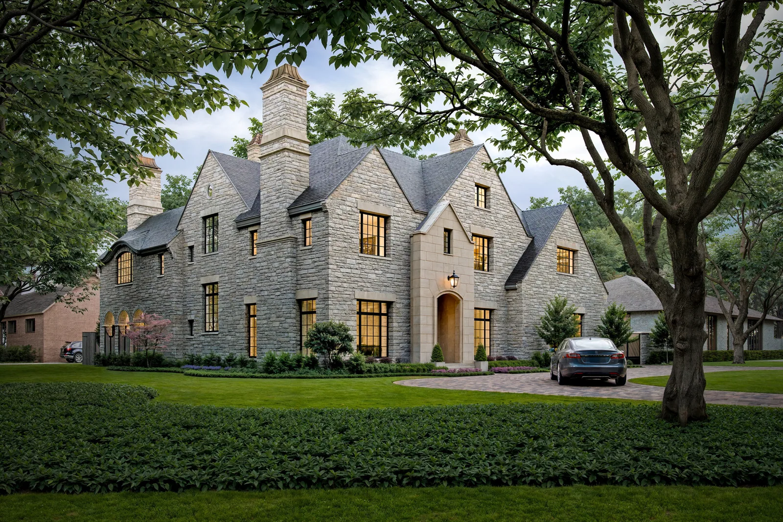 Stone manor house at 5665 Green Tree in Houston's Tanglewood with steep gables under oaks at dusk