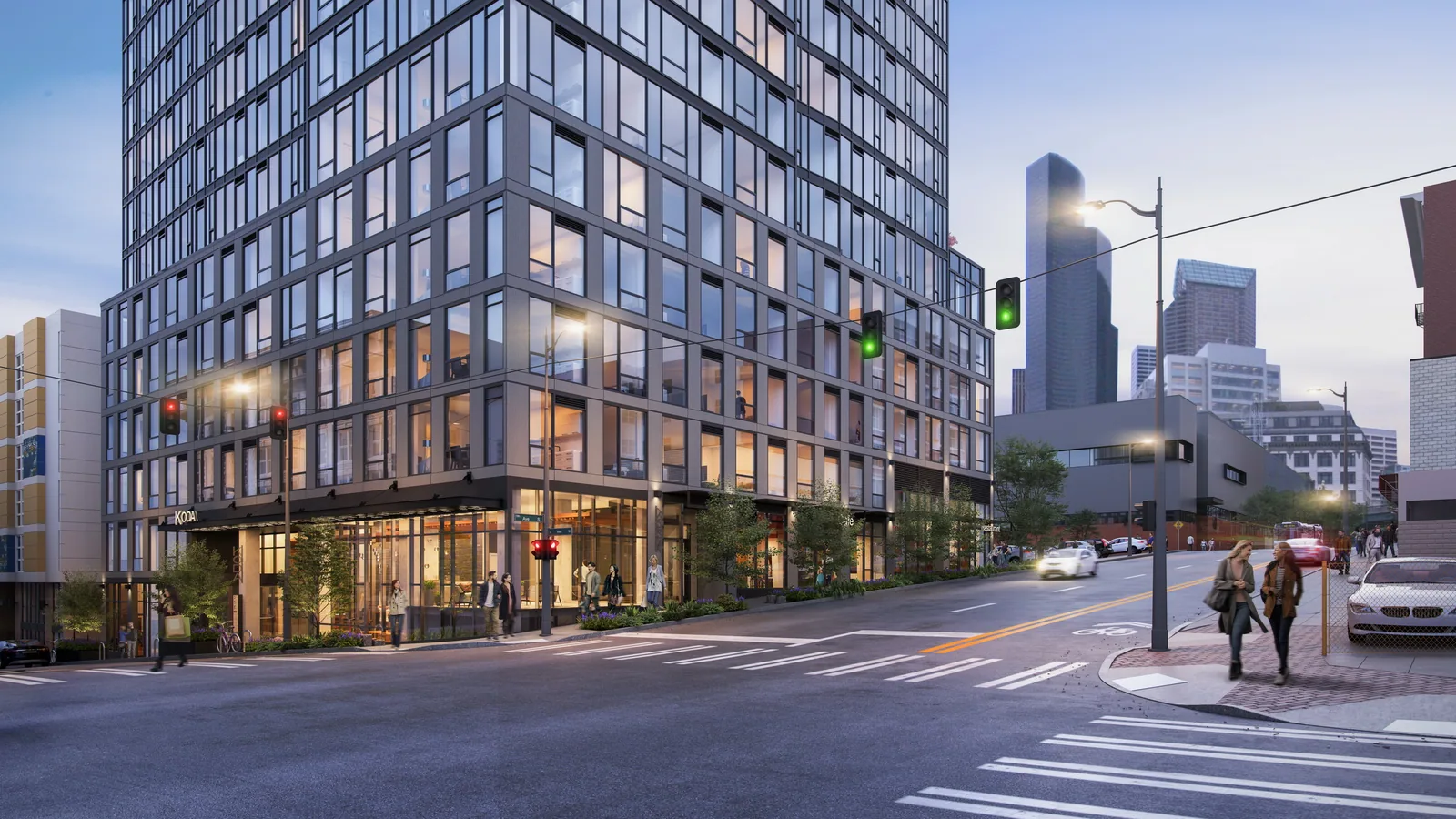 Street corner at the base of KODA Condominiums in Seattle at dusk with the downtown skyline