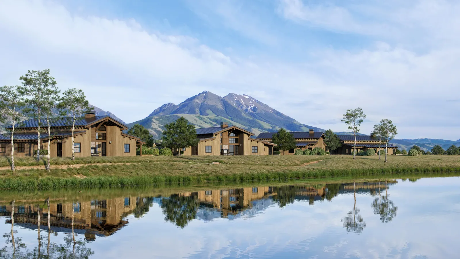 Sage Lodge buildings reflected in a pond below a mountain peak near Pray, Montana