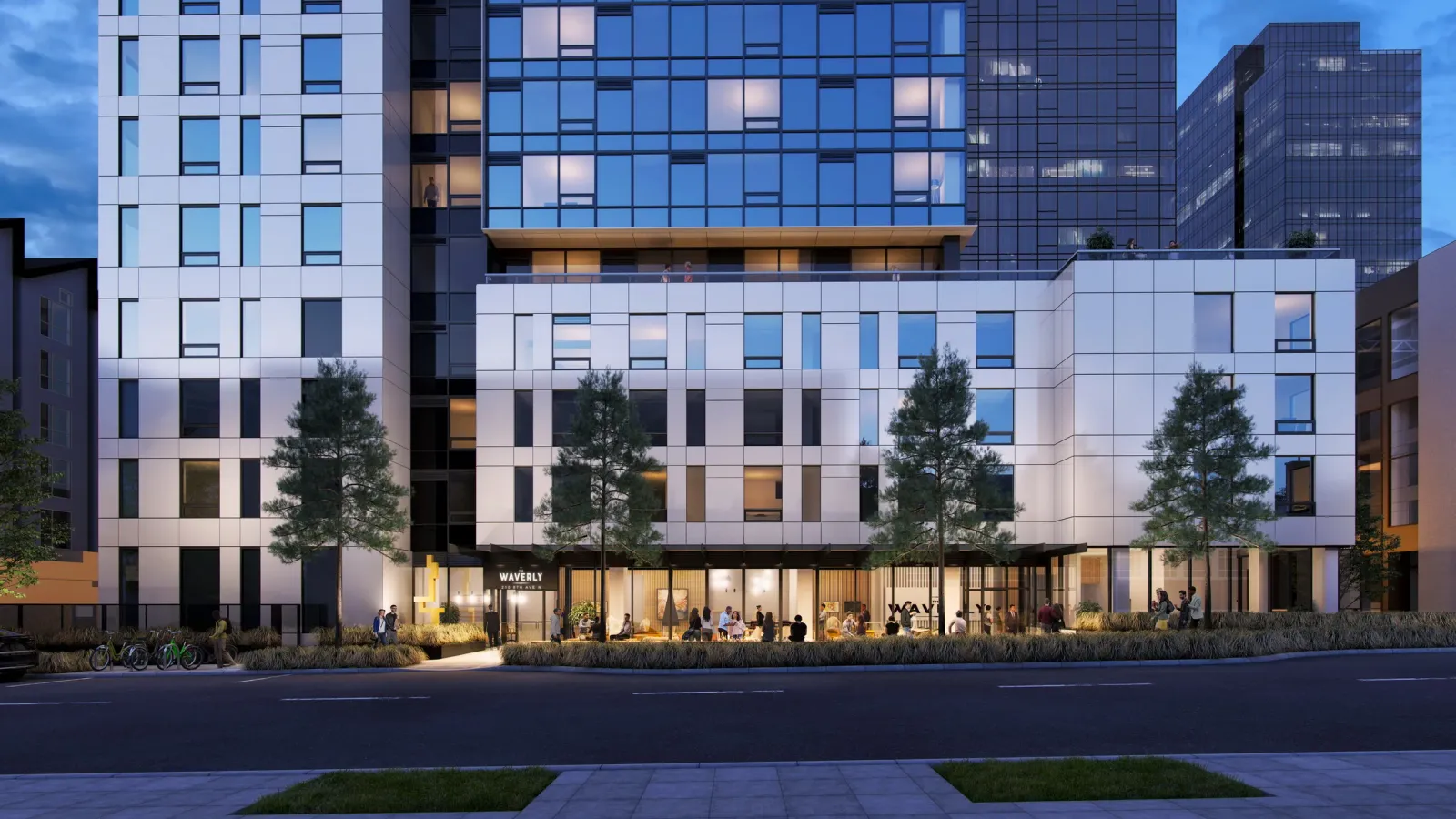 White and glass base of The Waverly residential tower in Seattle at dusk from the street
