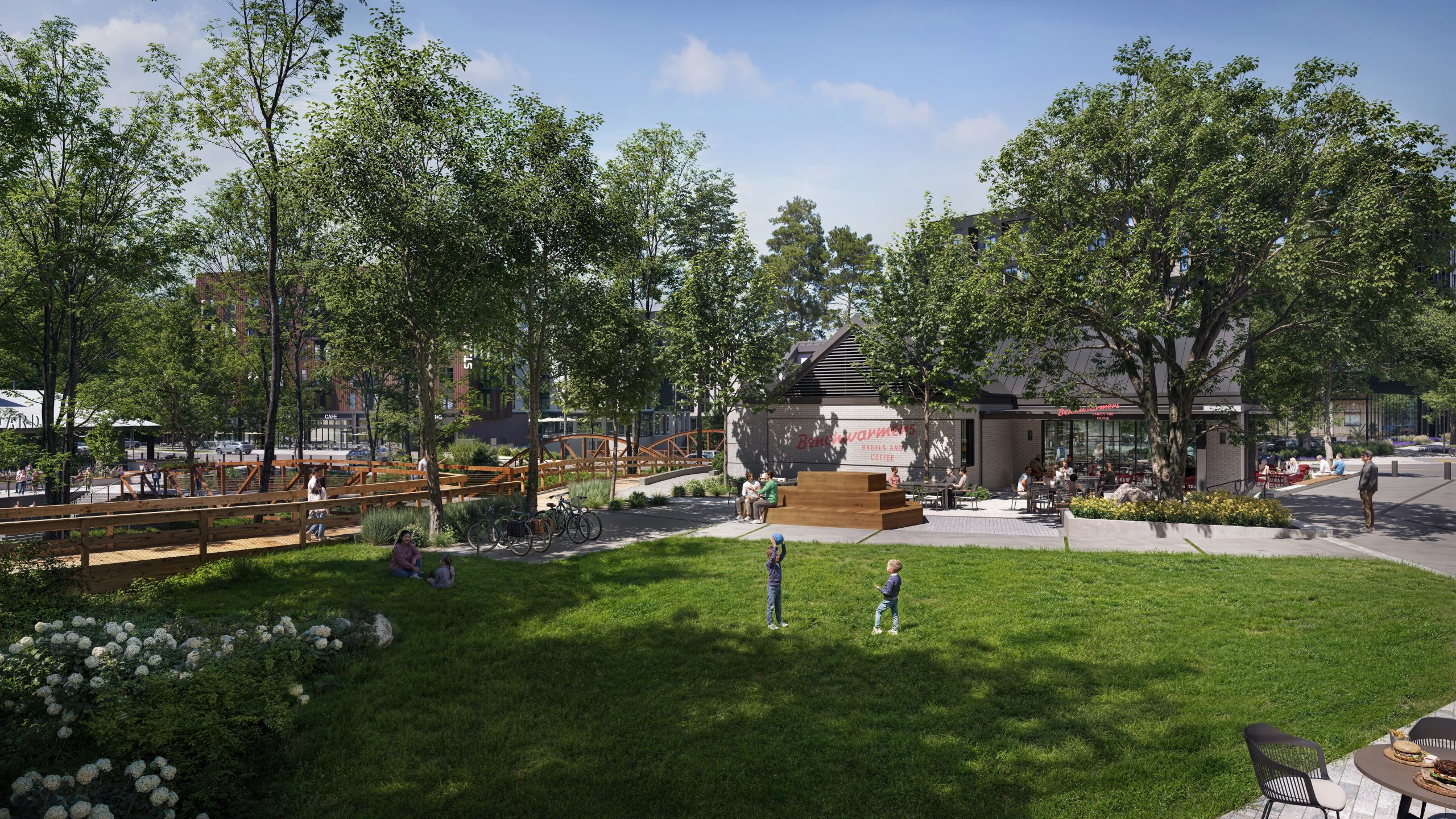 Benchwarmers Bagels at NHID Raleigh exterior rendering by Bogza.com. A vibrant daytime view of the local eatery nestled along the greenway, highlighting a lush outdoor gathering lawn, children playing, outdoor seating, and the wooden pedestrian bridge crossing the natural creek bed.