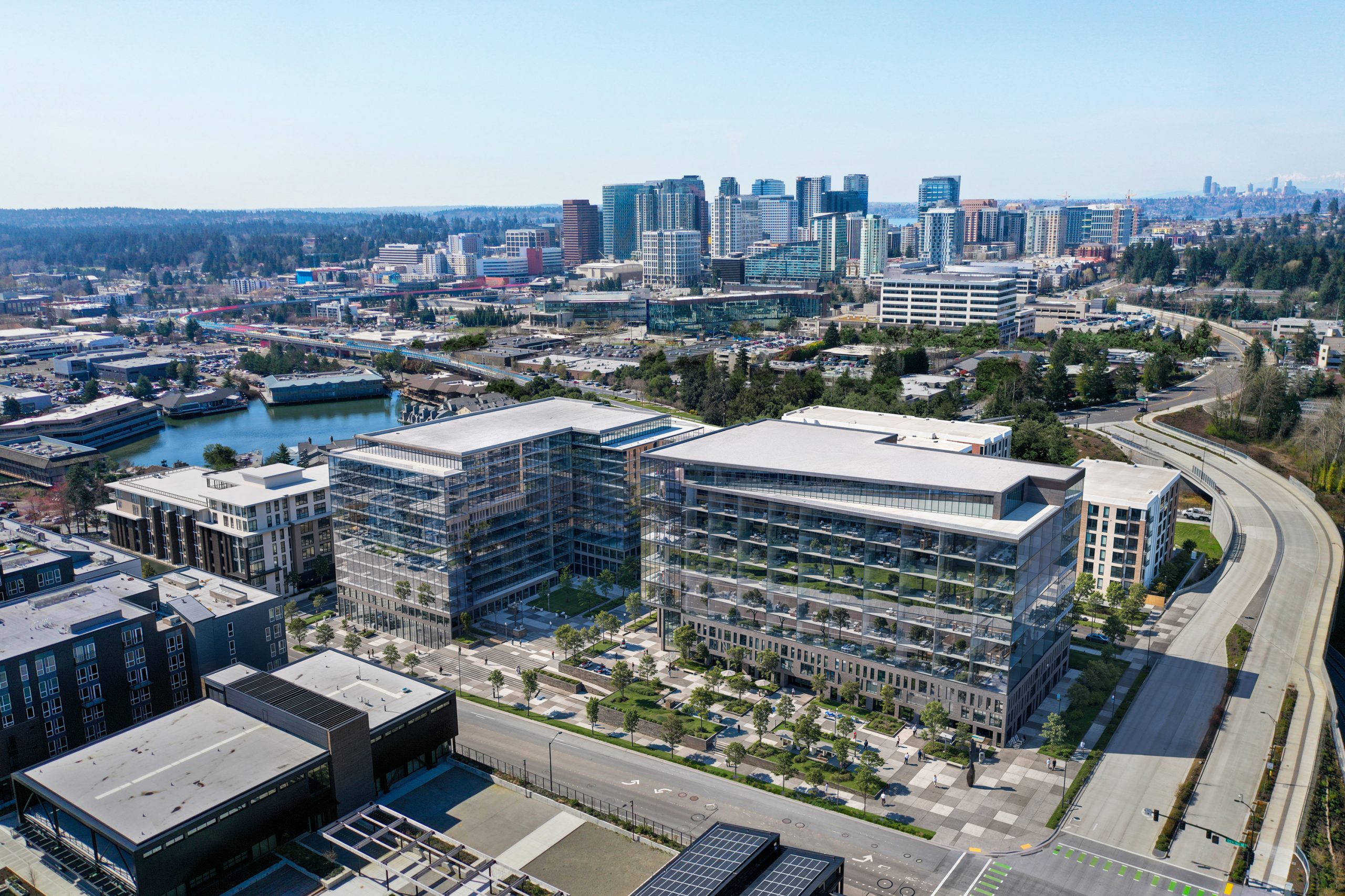 12th Place Development Bellevue aerial architectural rendering by Bogza.com. An elevated view of the Spring District master plan featuring modern glass office buildings and mid-rise residential apartments next to an elevated light rail track.