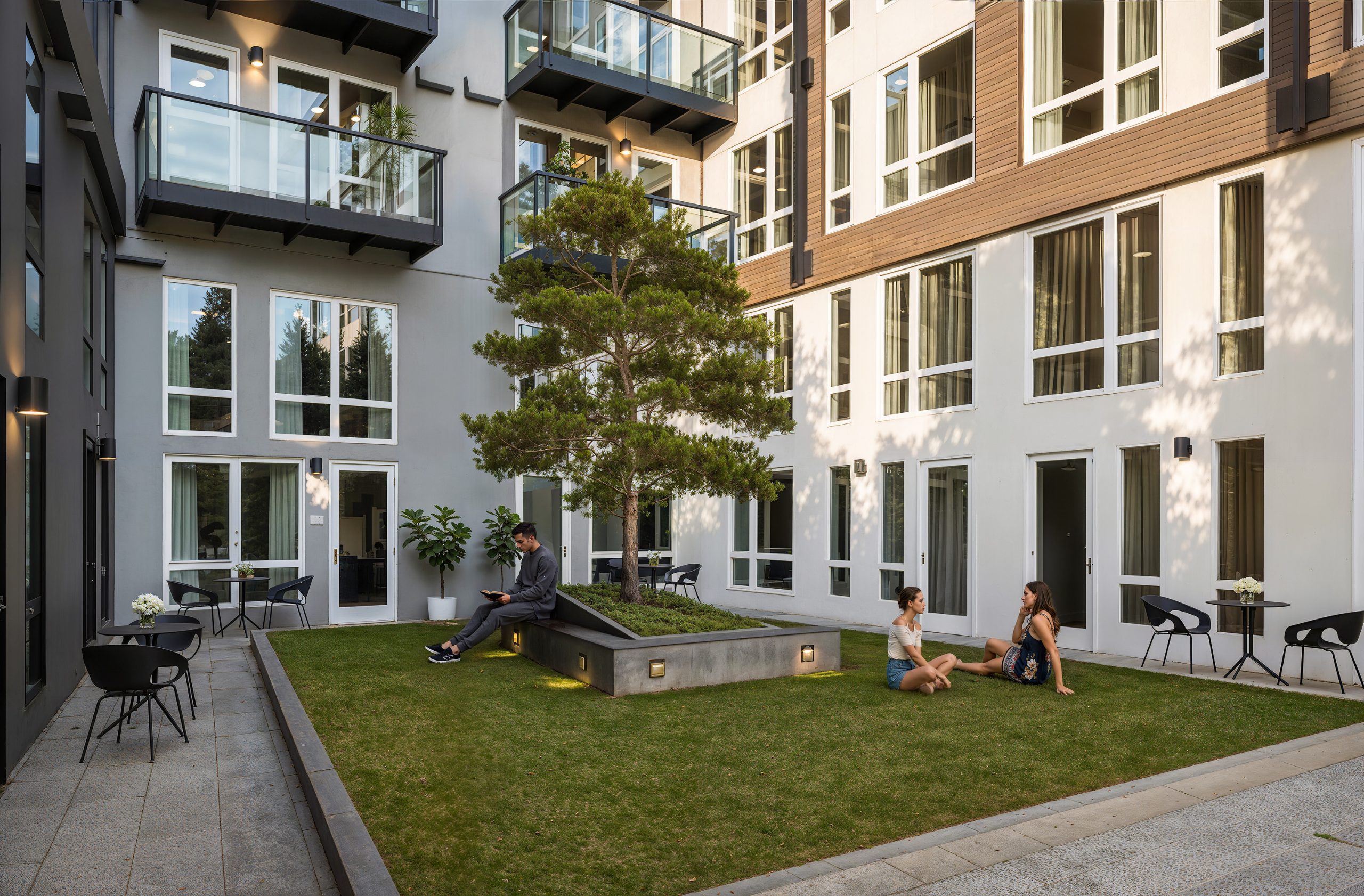 Broadstone Strata Seattle residential courtyard architectural rendering by Bogza.com. A ground-level view of a tranquil outdoor patio space for the luxury apartments, featuring a central lawn with a feature tree, modern seating arrangements, and residents relaxing outside their private patios.