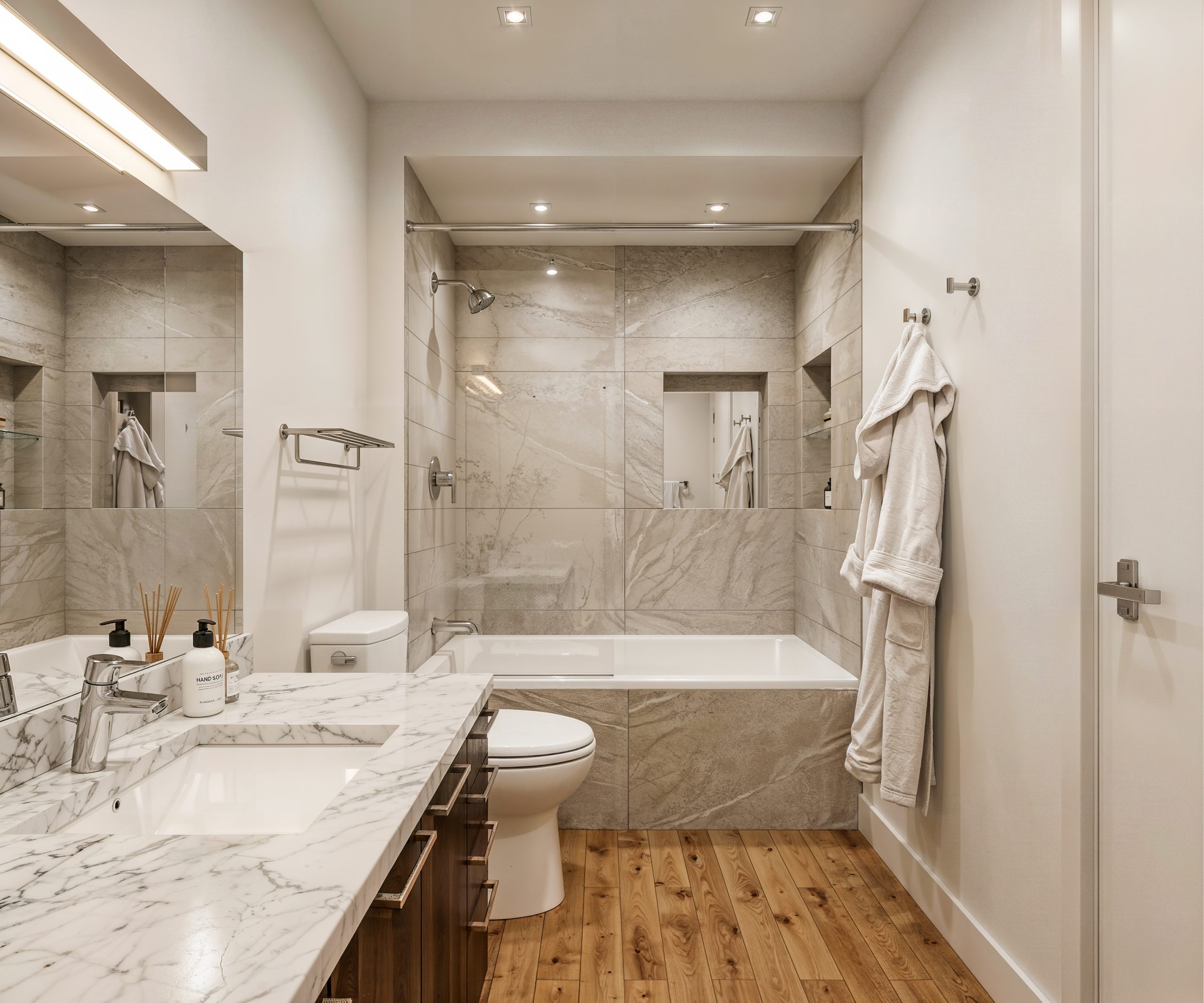Hyde Square Bellevue modern apartment bathroom interior architectural rendering by Bogza.com. A sleek, elegant bathroom featuring a walk-in shower with large grey tile surrounds, a white marble vanity with dark wood cabinetry, and wood-style flooring.