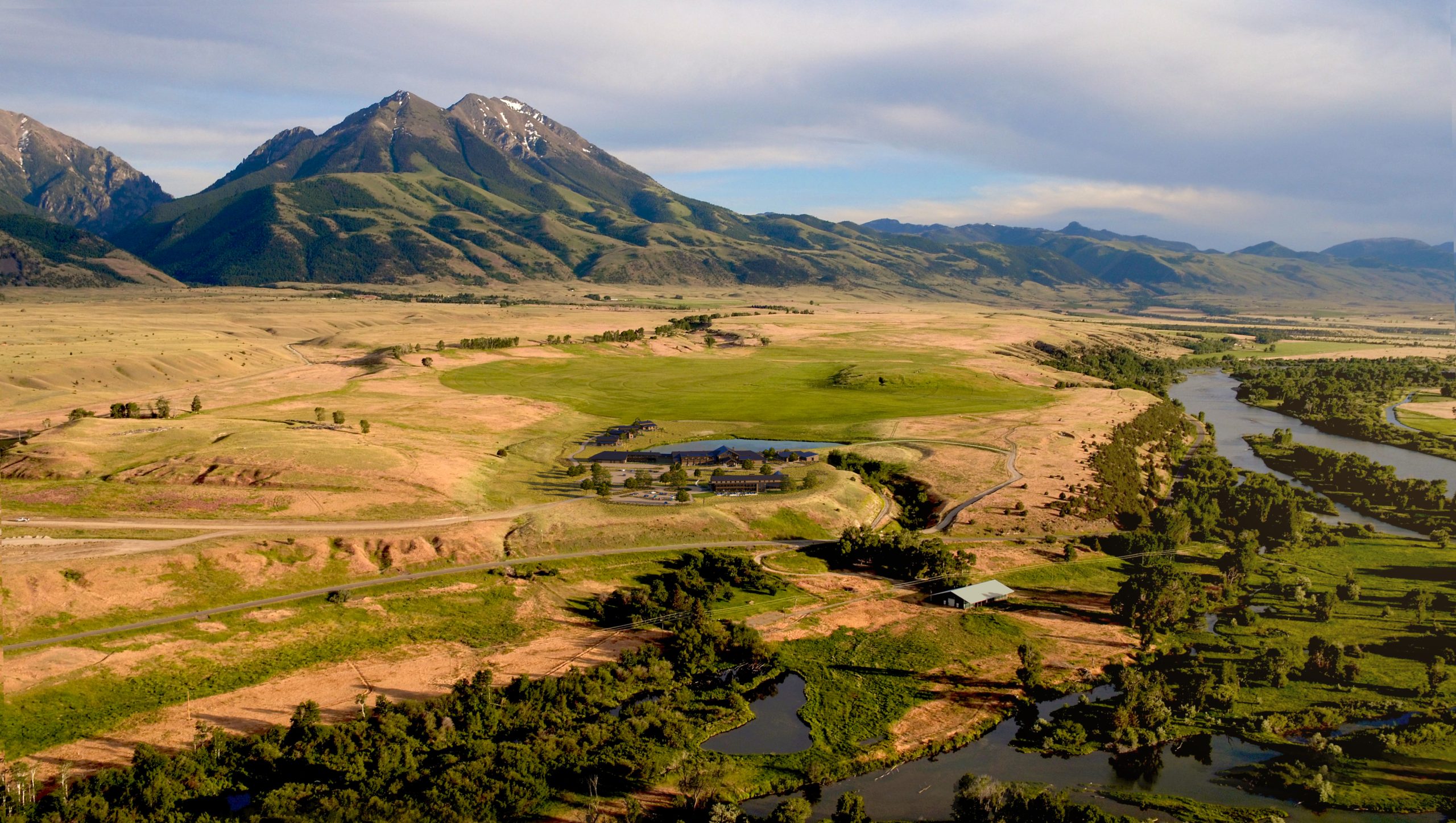 Sage Lodge Paradise Valley aerial exterior architectural rendering by Bogza.com. A breathtaking daytime drone view of the expansive luxury resort set in the sweeping Montana landscape, featuring the winding Yellowstone River and the majestic Emigrant Peak in the background.