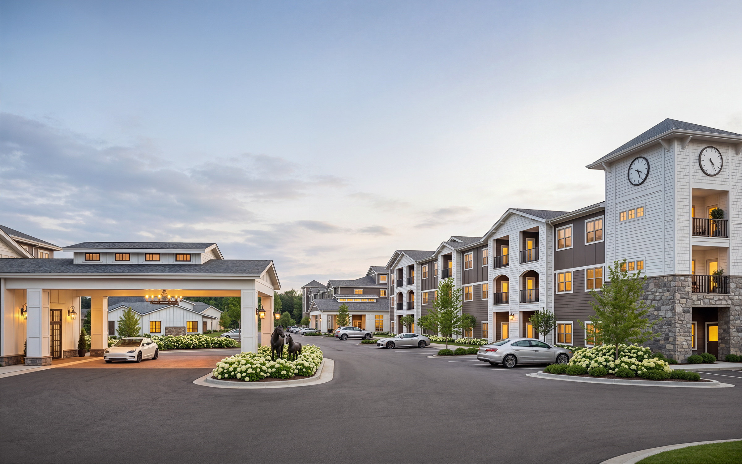 University Village retirement community exterior architectural rendering by Bogza.com. A twilight view showcasing the multi-story senior living complex, a clock tower building, the grand porte-cochere, lush flower landscaping, and parked cars.