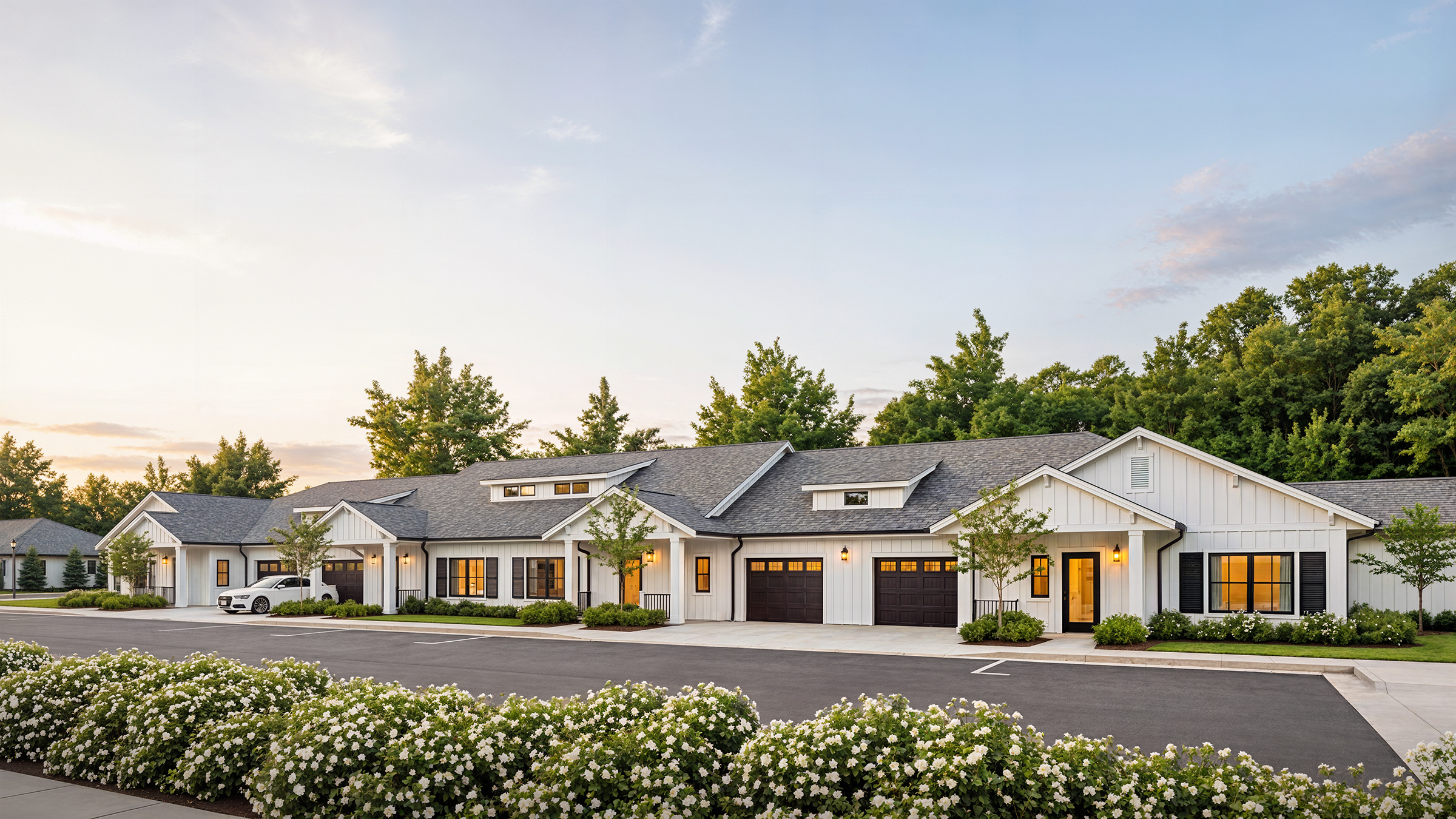 University Village independent living cottages exterior rendering by Bogza.com. A serene twilight view of the single-story classic white cottages with dark shutters and attached garages, surrounded by lush native landscaping and pristine white flowers.