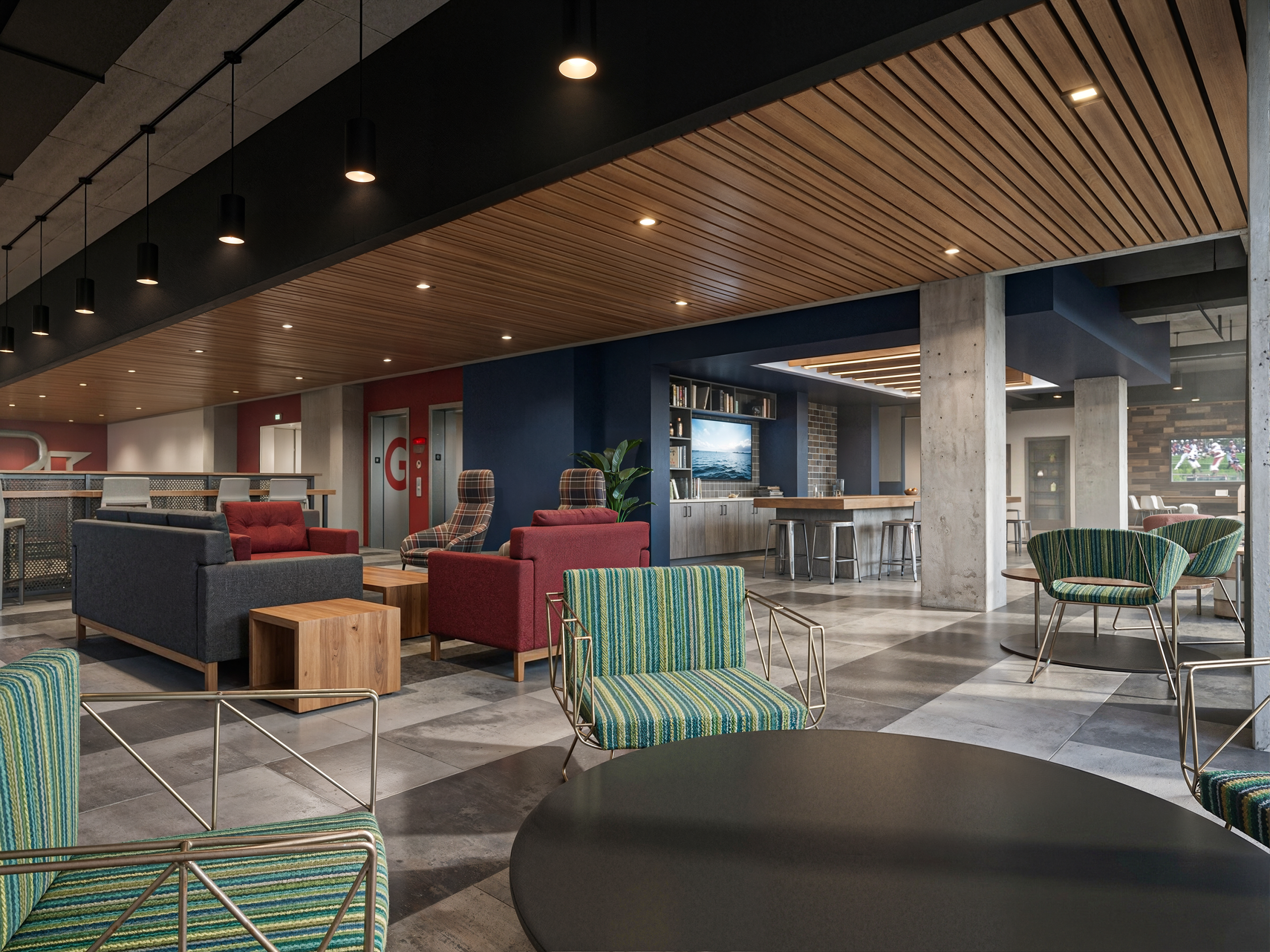 Vi Hilbert Hall Seattle University student clubhouse and lounge interior rendering by Bogza.com. A vibrant community gathering space featuring a warm wood-slat ceiling, exposed concrete columns, colorful modern armchairs, a flat-screen TV, and red elevator doors.